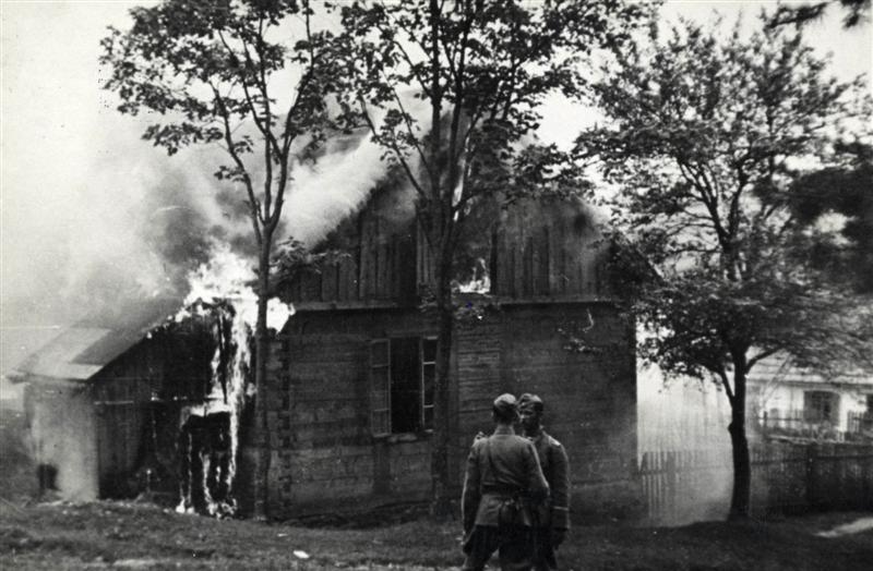 Dwaj niemieccy policjanci na tle płonącego domu w Michniowie w dniu 12 lipca 1943